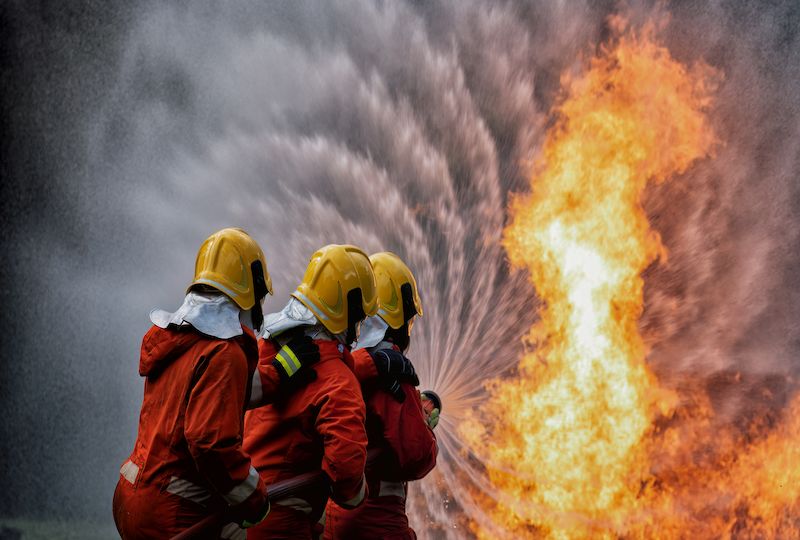 fire fighter team on training with gas and oil fire hold hose spray jet water spray to extinguish