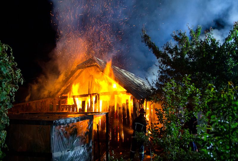 Wooden house or barn burning on fire at night.